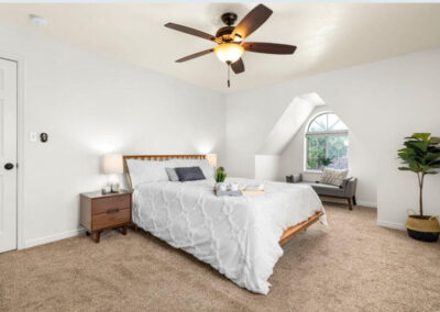 white bedding in master bedroom with lounge in window cutout