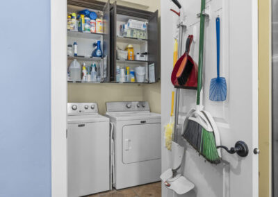 Laundry room with open cupboards showing laundry supplies