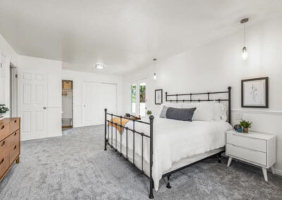 Master bedroom with iron bed and white bedding in staged home for sale