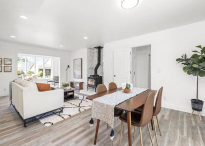 Home Staging in Orem with cream sofa, mid-century modern coffee table and wood burning stove and dining table and chairs in foreground