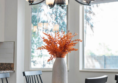 detail of modern farmhouse dining table with white vase and orange-leafed branches
