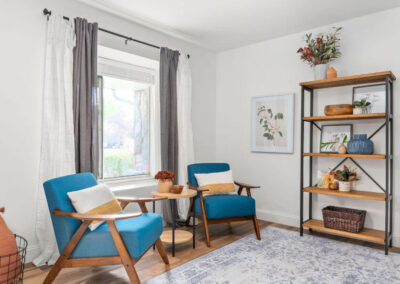 redesigned sitting area with blue chairs and wood and metal bookshelf with clean modern decorations