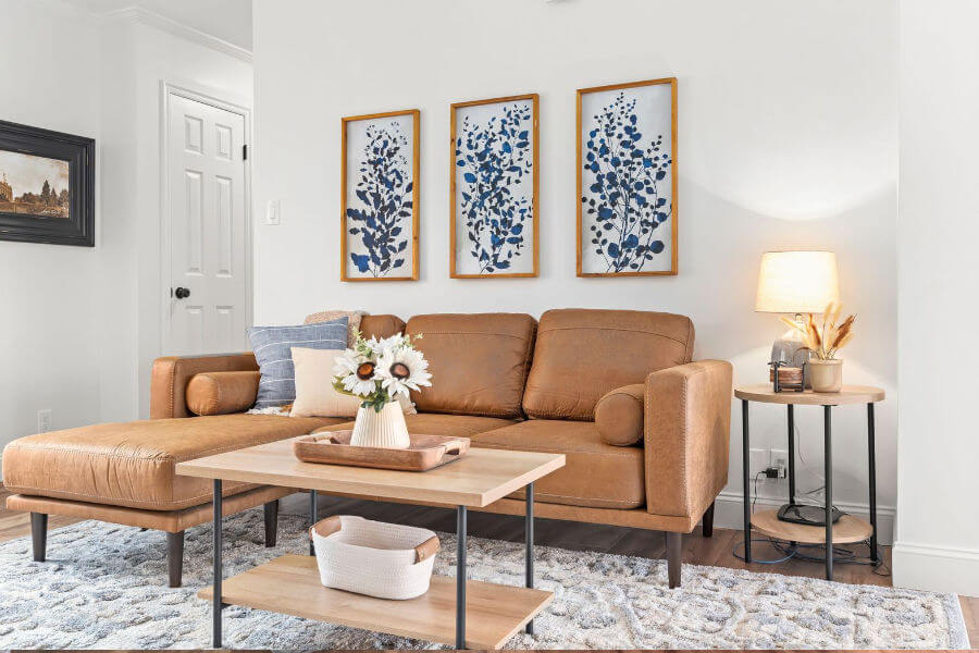 Interior design in Murray includes leather sectional sofa, wooden industrial farmhouse tables and artwork