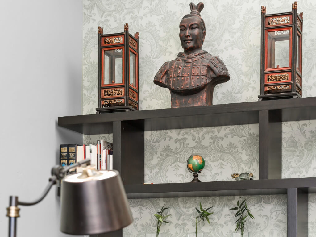 Sun-Tzu bust and lanterns on bookshelf with bamboo and other decor