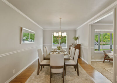staged formal dining room with dark wood table and grey plush chairs and rug