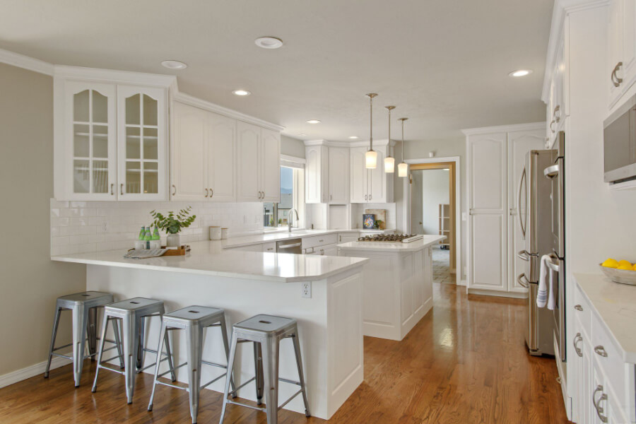 beautiful white kitchen with island and industrial style stools staged in south jordan