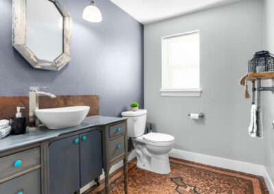 small bathroom furnished and decorated with penny-floor, blue-grey cabinets and other decor