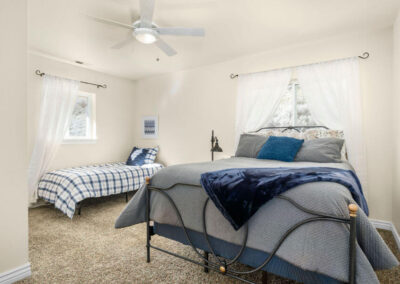 two blue and gray beds in a bedroom with white drapes