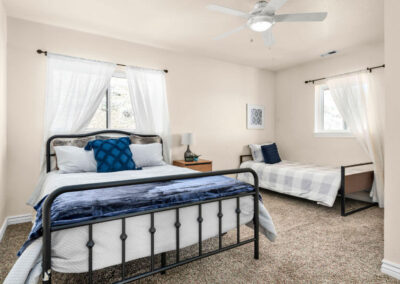 two beds in a bedroom with blue pillow and throw