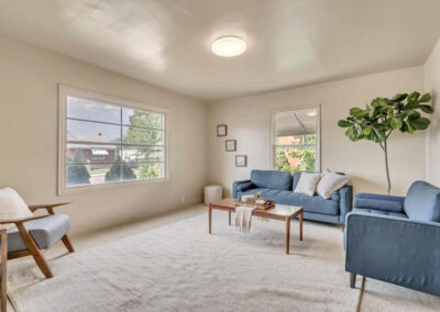 sitting room staged with blue sofa and loveseat, gray and wood chair plus coffee table and fiddle leaf fig plant